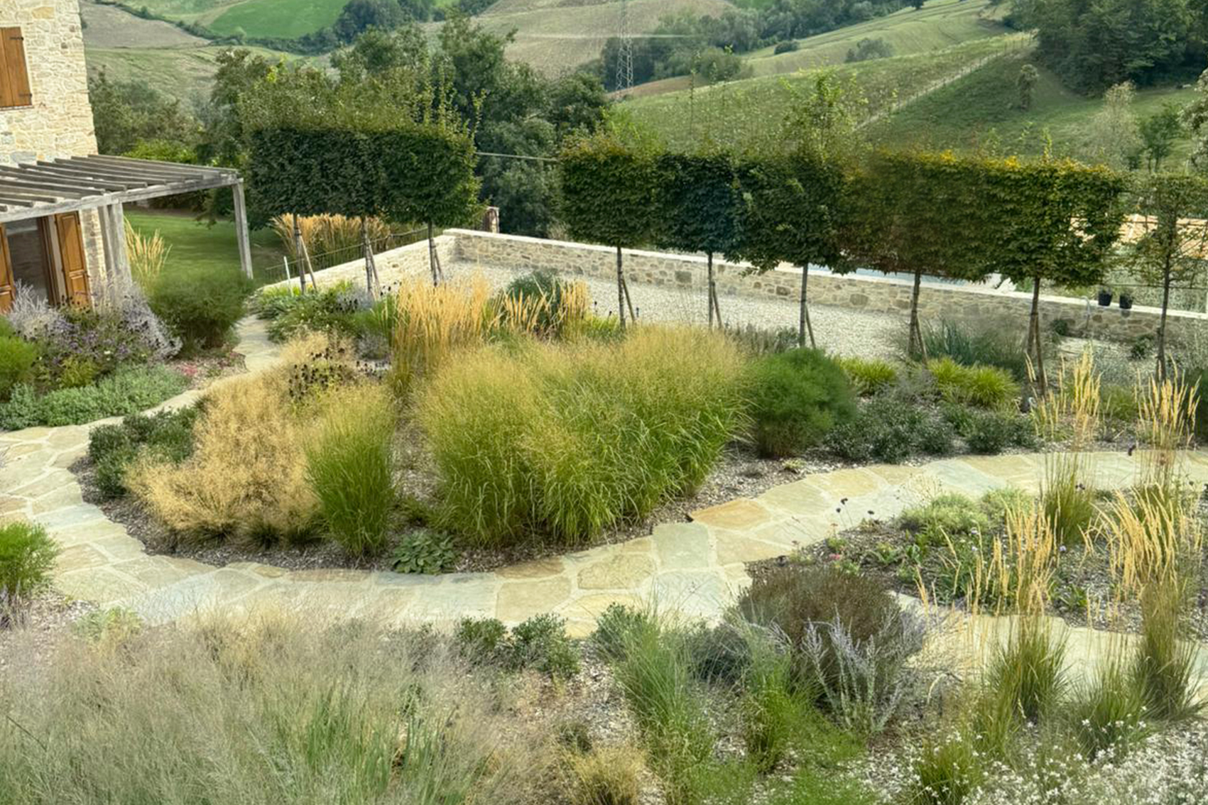 Giardino colline parmensi grande giardino privato con aiuole di piante perenni e graminacee realizzato colline parmense progettazione di ampio giardino con isole verdi e composizioni di piante ornamentali realizzazione paesaggistica di giardino con siepi e aiuole miste nelle colline parmensi